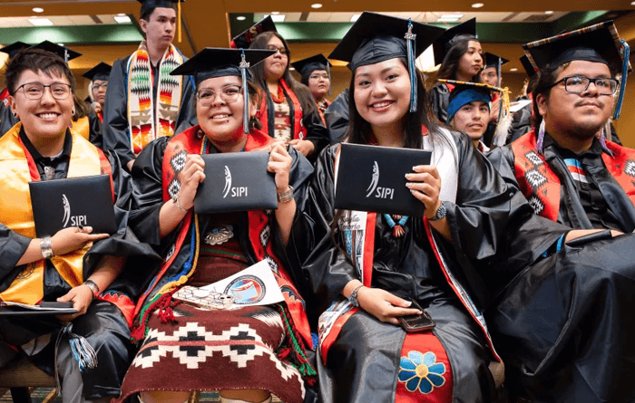 Graduates in caps and gowns proudly holding their diplomas.