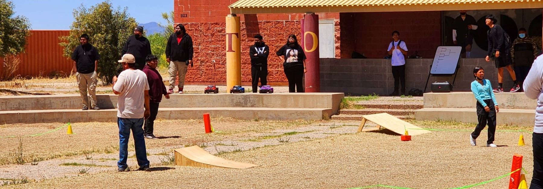 A group of students using remote control cars, enjoying their time outdoors together.