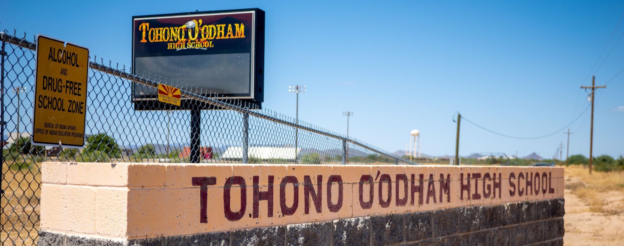 Sign outside Tohono O'odham High School with the school name painted on the wall.