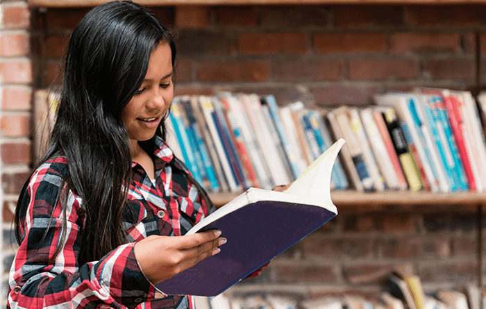 Female teen reading a book in the library. 