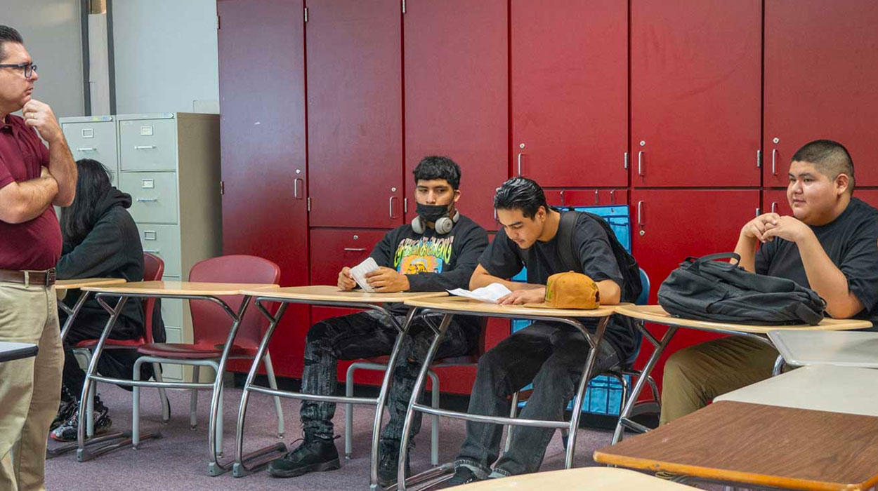 Teacher in classroom speaking to students. 