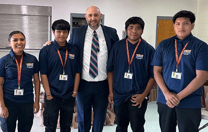 Male principal with four young male students posing for the camera. 